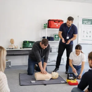 Students taking part in a First Aid at Work (FAW) training course, practising CPR and emergency response skills with a qualified instructor.